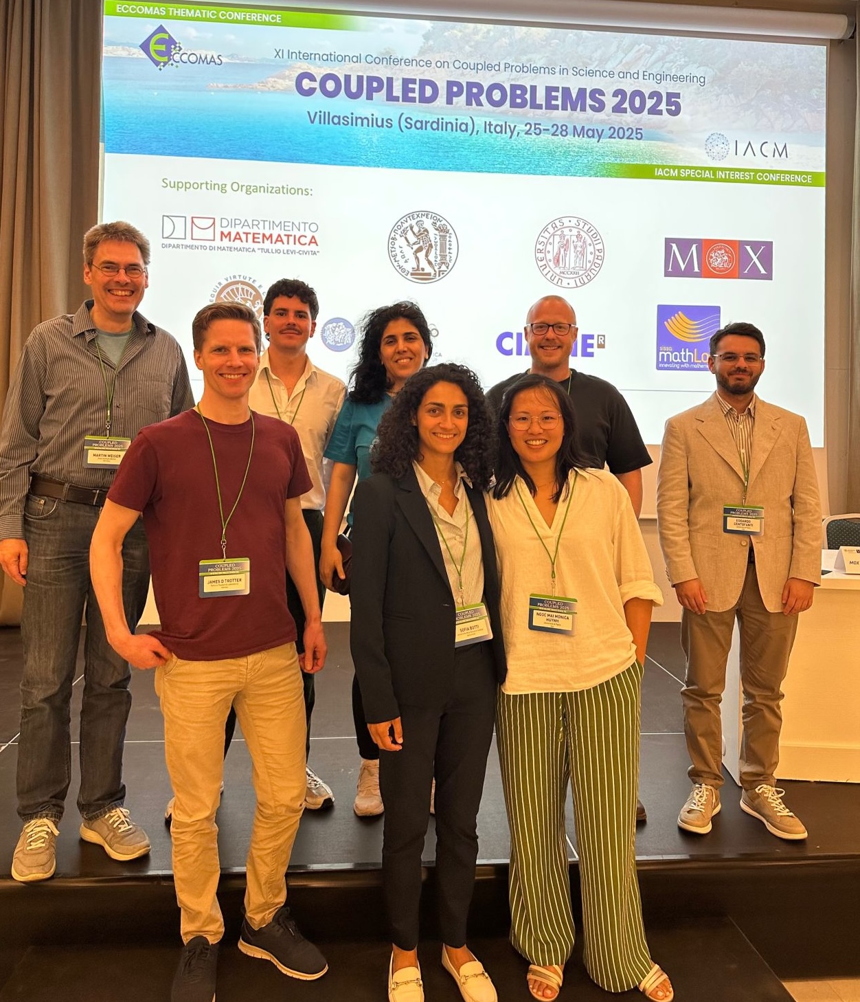 Current and former members of MICROCARD posing in a conference
room at the COUPLED25 meeting.